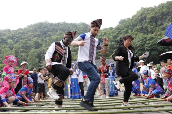 ▲外国游客体验跳竹竿舞,感受中华民族一家亲。(樊绍光 摄)